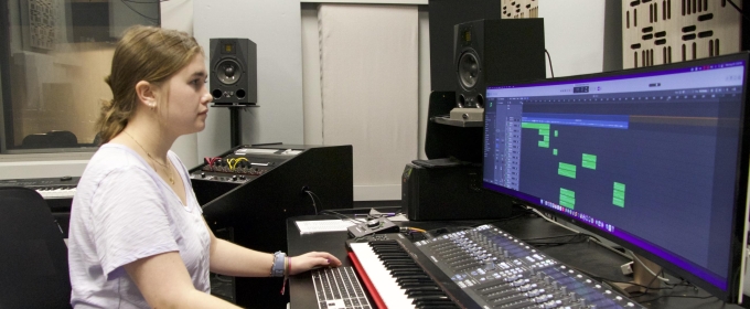 photo of student sitting at sound board with computer screen