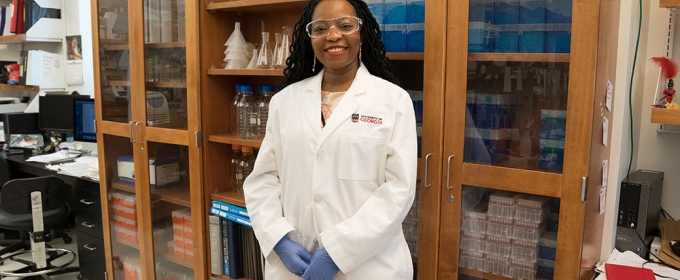 photo of woman in laboratory, in what lab coat with shelves and bottles