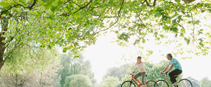 photo of two people biking, day, with field 