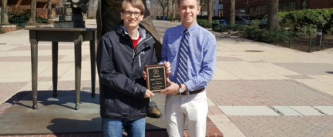 two students with plaque in front of statue