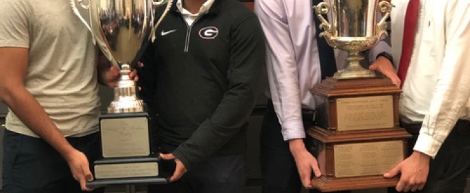 photo of four men holding two trophies 