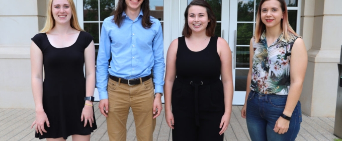 Photo of four scholarship awards winners outside in front of a building