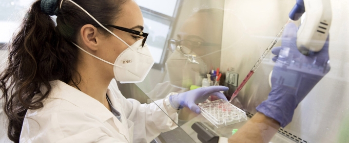 photo of scientists in lab with mask, gloves, pipette