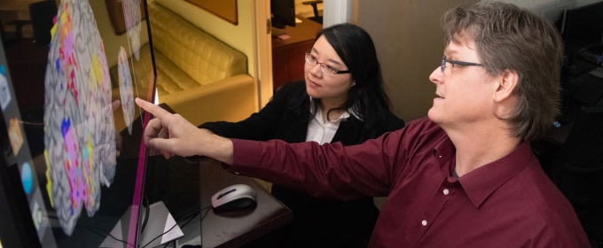 photo woman and man pointing to computer screen