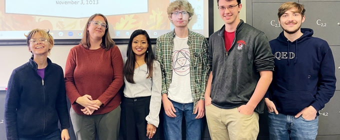 group photo of six people, with projection screen in background