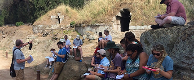 students with professor at ancient tomb opening