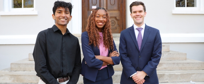 photo of three people, building in background, day