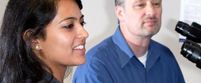 student with professor and microscope