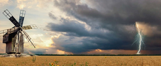 field with windmill and approaching storm