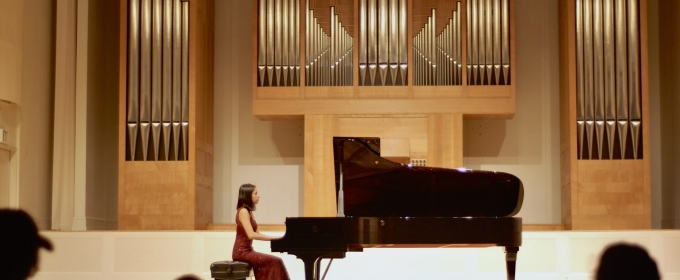 photo of woman in piano performance, with audience silhouette foreground