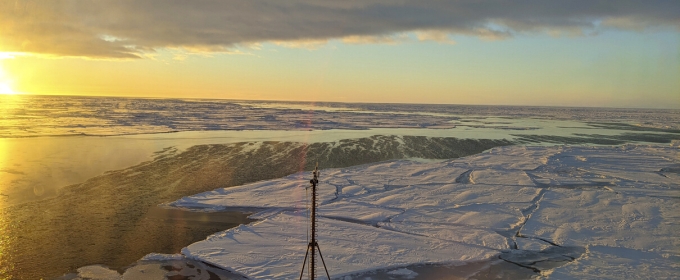 photo of sunrise over frozen sea, with bow of ship