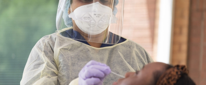 photo of masked nurse administering nasal swab test to patient