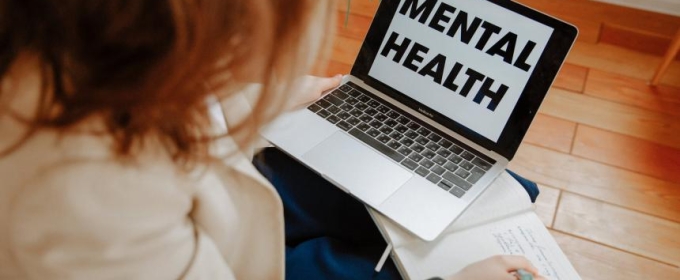 photo of person with laptop open, writing in a book