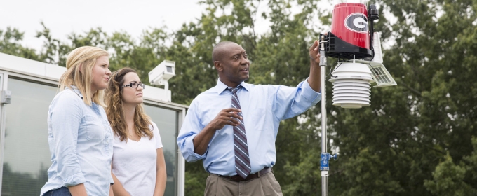 photo of man, two women, and rain/wind gauge, outdoors, 